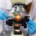 technician looking at slide under a microscope