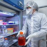 research technician remvin vial of cells from refrigerator